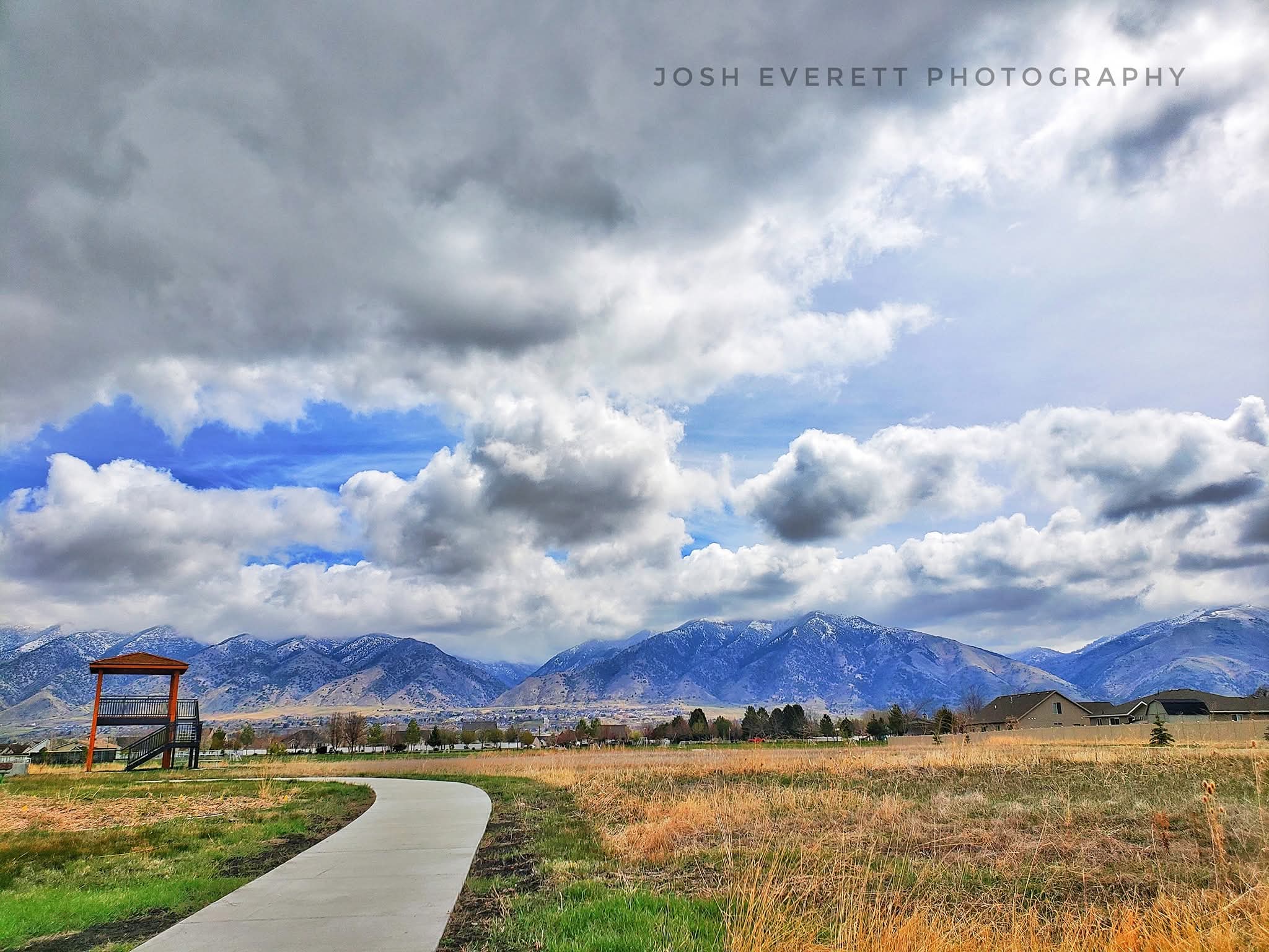 Curving sidewalk with a watch tower and mountains in the background.
