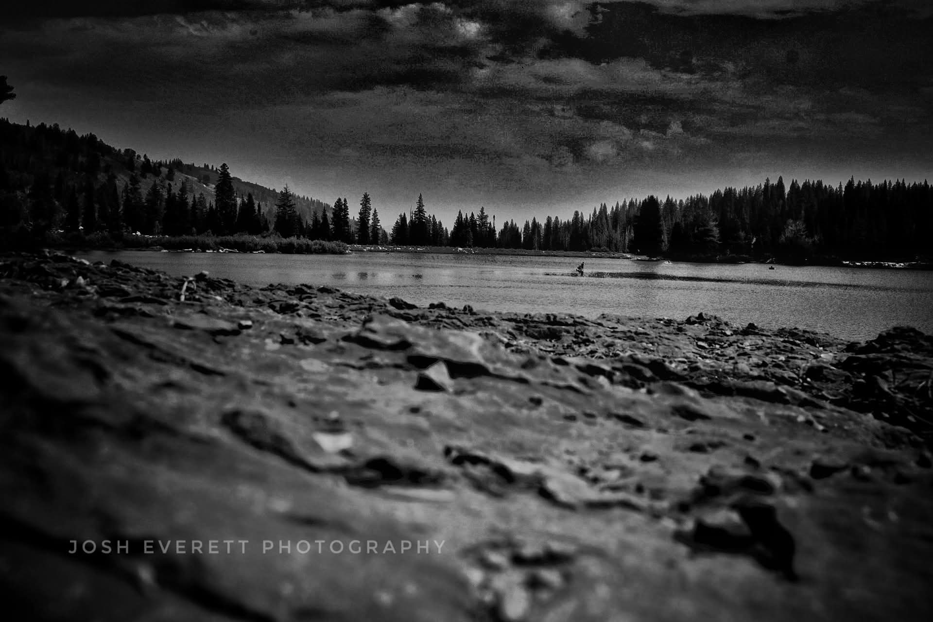 Black and white, tree and mountain surrounded lake.